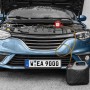 APA Ölabsaugpumpe 12V im Einsatz an einem Auto mit geöffneter Motorhaube, Öl läuft in Kanister.