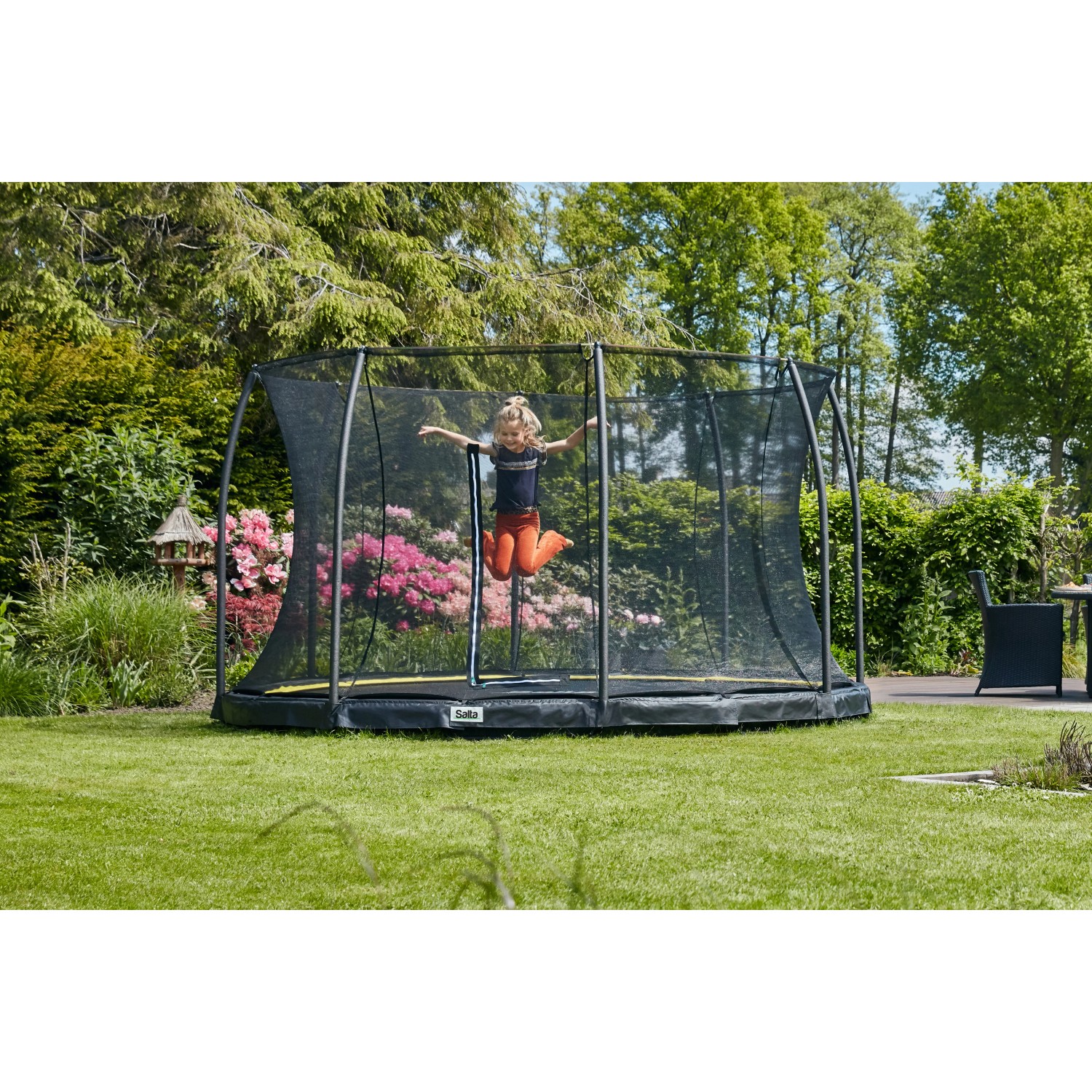 Schwarzes Salta Comfort Edition Bodentrampolin (ø 305 cm) mit Sicherheitsnetz und springendem Kind im Garten.