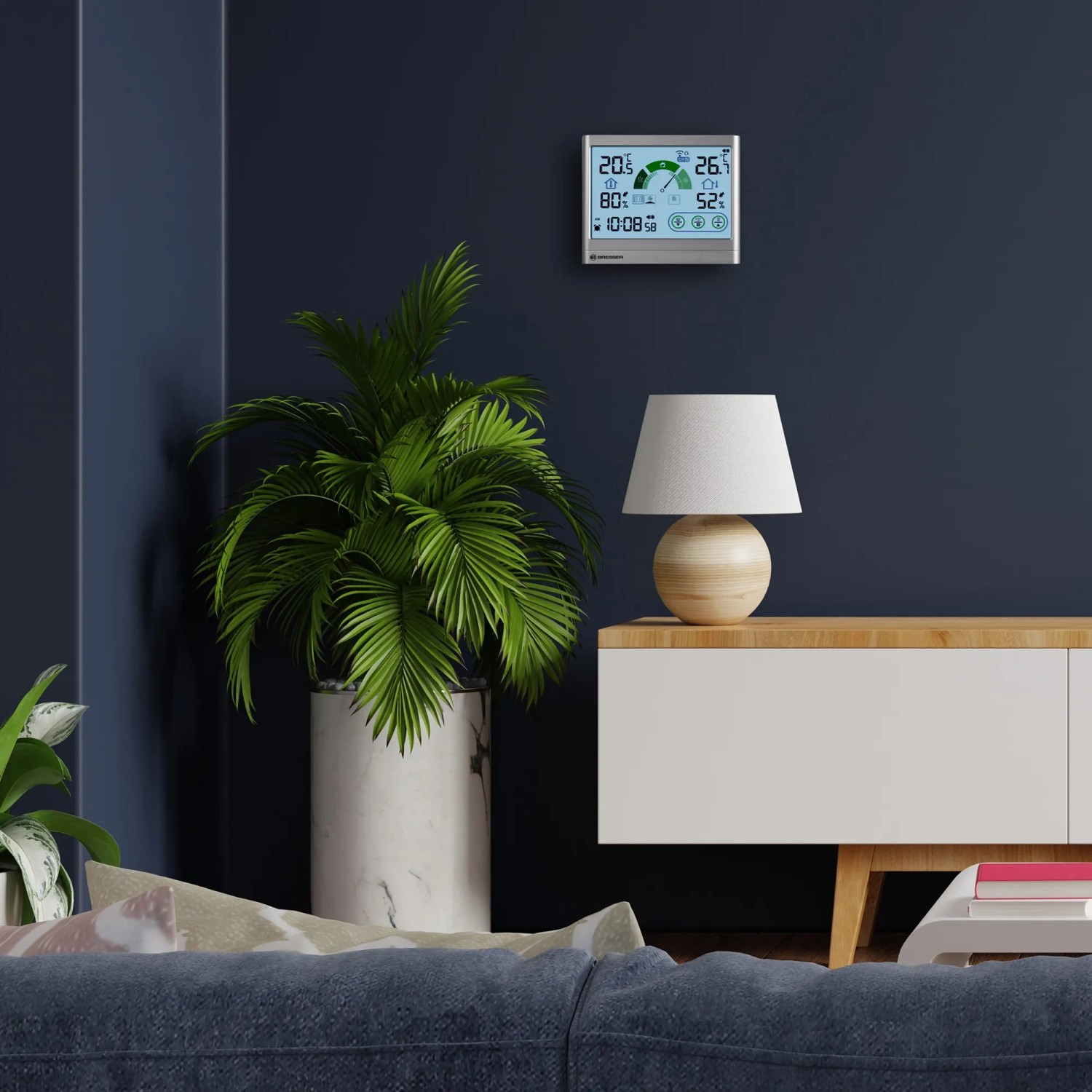Bresser VentAir H Thermo-Hygrometer in Anthrazit an Wand über Sideboard mit Lampe und Pflanze.