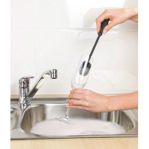 Anthrazitfarbene Wenko Silikon Spülbürste (25 cm) reinigt ein Glas in der Spüle.