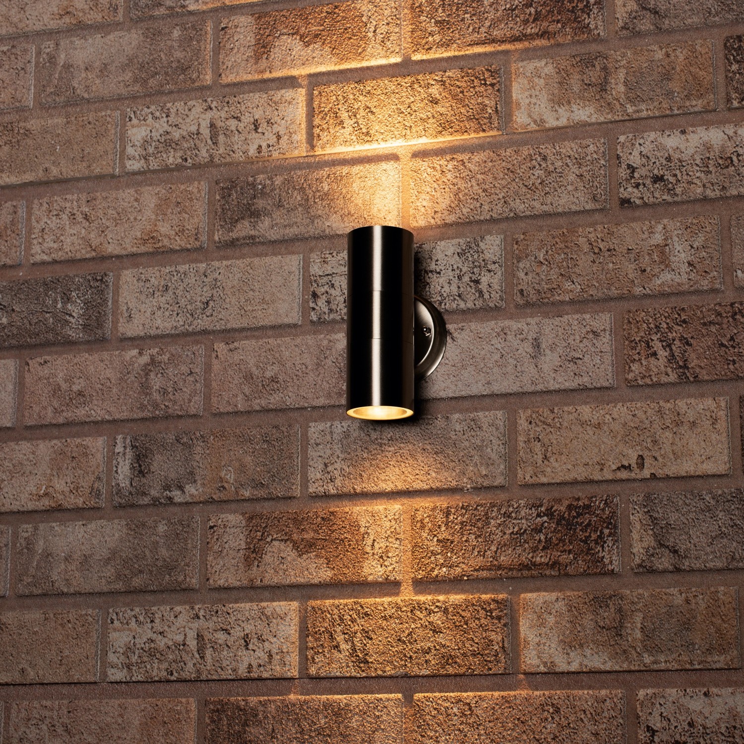 Moderne, runde 2-flammige LED Außenwandleuchte aus Edelstahl an einer Backsteinwand.