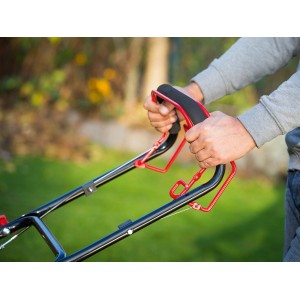 Detailaufnahme: Hände bedienen den Griff des CMI Benzin-Rasenmähers. Ergonomisches Design für komfortables Rasenmähen.