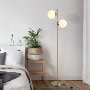 Moderne goldene Stehlampe mit zwei weißen Glaskugeln im Schlafzimmer. Ideal als Innenleuchte.