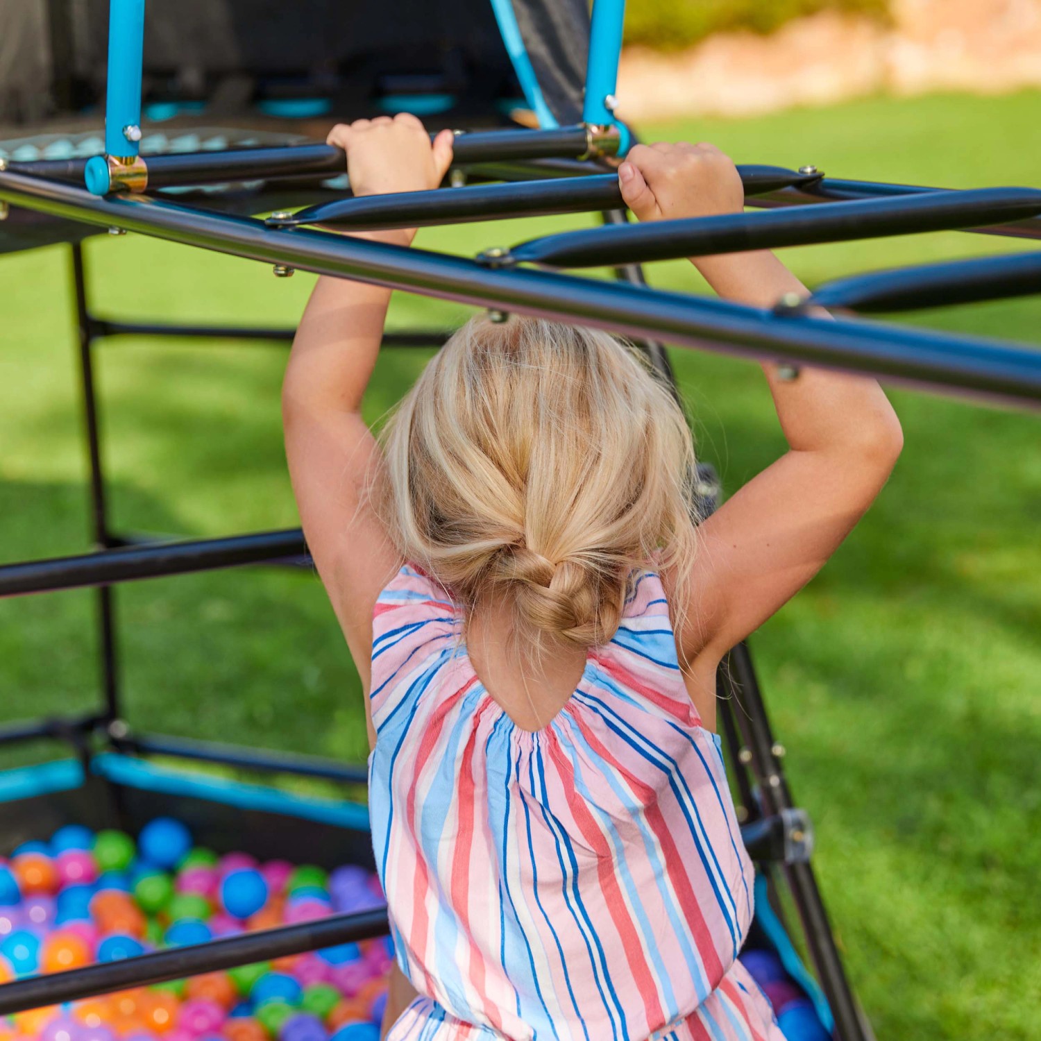 Kind klettert auf schwarzem TP Toys Klettergerüst Explorer mit Bällebad. Spielturm für Kinder.