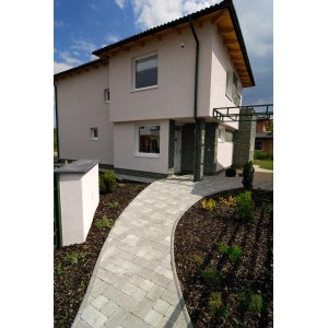 Verlegtes Premac Pflaster Graniko Grau (21x14x6 cm) als Gartenweg zu einem Haus.