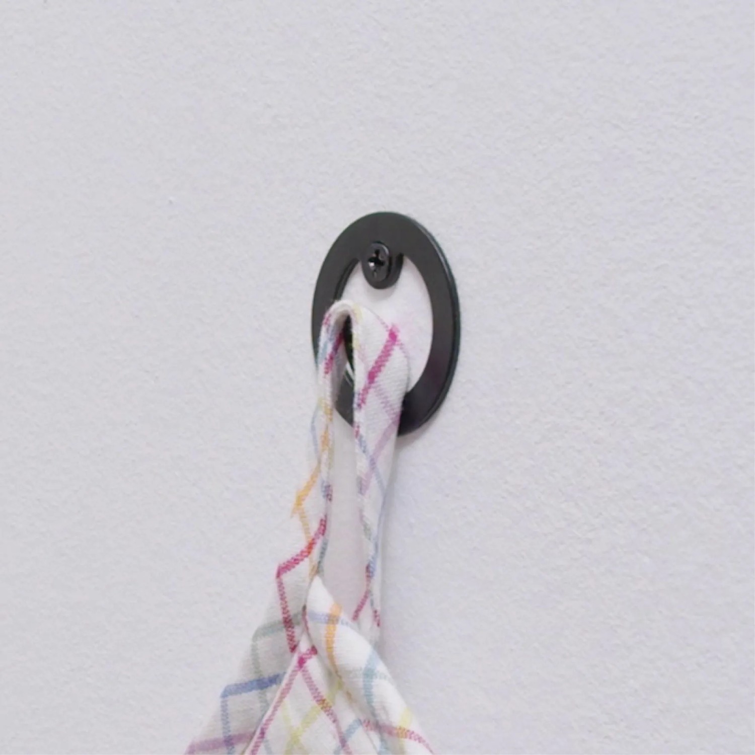 Schwarzer, matter Wagner Wandhaken Hooks4home Retro mit Handtuch an weißer Wand.