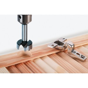 Wolfcraft Forstnerbohrer (35 mm) beim Bohren eines Lochs in Holz, neben einem Scharnier.