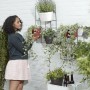 Frau bepflanzt Elho Wandhängetopf Loft Urban Duo (weiß) am Wandgitter. Hängetöpfe für vertikalen Garten.