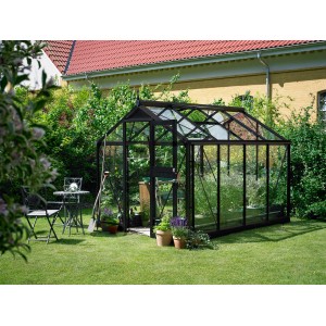 Juliana Gewächshaus Compact 6 in Anthrazit im Garten, mit Pflanzen und Gartengeräten.