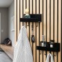 Schwarzes DenPanels Regal mit 4 Stiften an Akustikpaneel mit Jacke, Schlüssel und Deko.