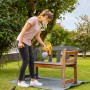 Frau sprüht Holzbank mit Wagner Farbsprühsystem W 125 im Garten.