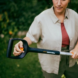 Frau bedient Fiskars Unkrautstecher X-Series mit D-Griff zur Bodenbearbeitung im Garten.