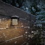 Schwarze Philips Solar-Außenwandleuchte Hara an einer Holzwand im Schnee.
