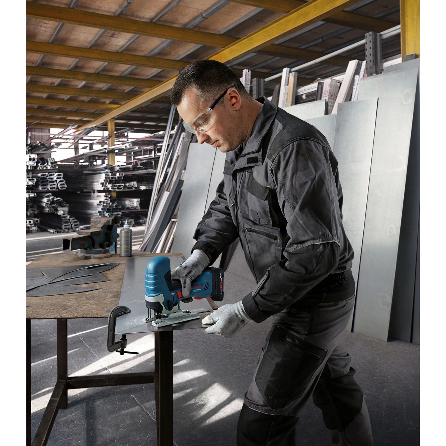 Mann schneidet Metall mit Bosch Professional Akku-Stichsäge GST 18 V-125 S. Blaue kabellose Stichsäge im Werkstatt-Einsatz.