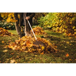 Person harkt Laub mit Fiskars Light Laubbesen. Leichter Aluminium-Stiel, flexible Zinken.