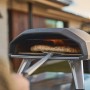 Ooni Koda 2 Gas-Pizzaofen, 2. Generation, schwarzgrau, mit Pizza auf dem Pizzastein.