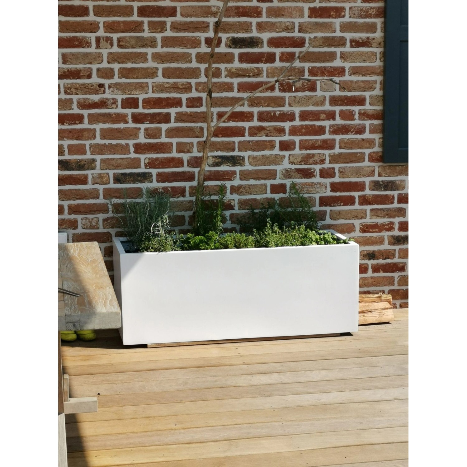 Weißer Vivanno Pflanzkübel Maxi (120x45x45 cm) aus Fiberglas, bepflanzt mit Kräutern, auf Holzterrasse.