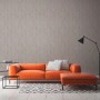 Vliestapete Trendwall 2 Uni Grau Silber Glänzend an Wohnzimmerwand hinter orangefarbenem Sofa.