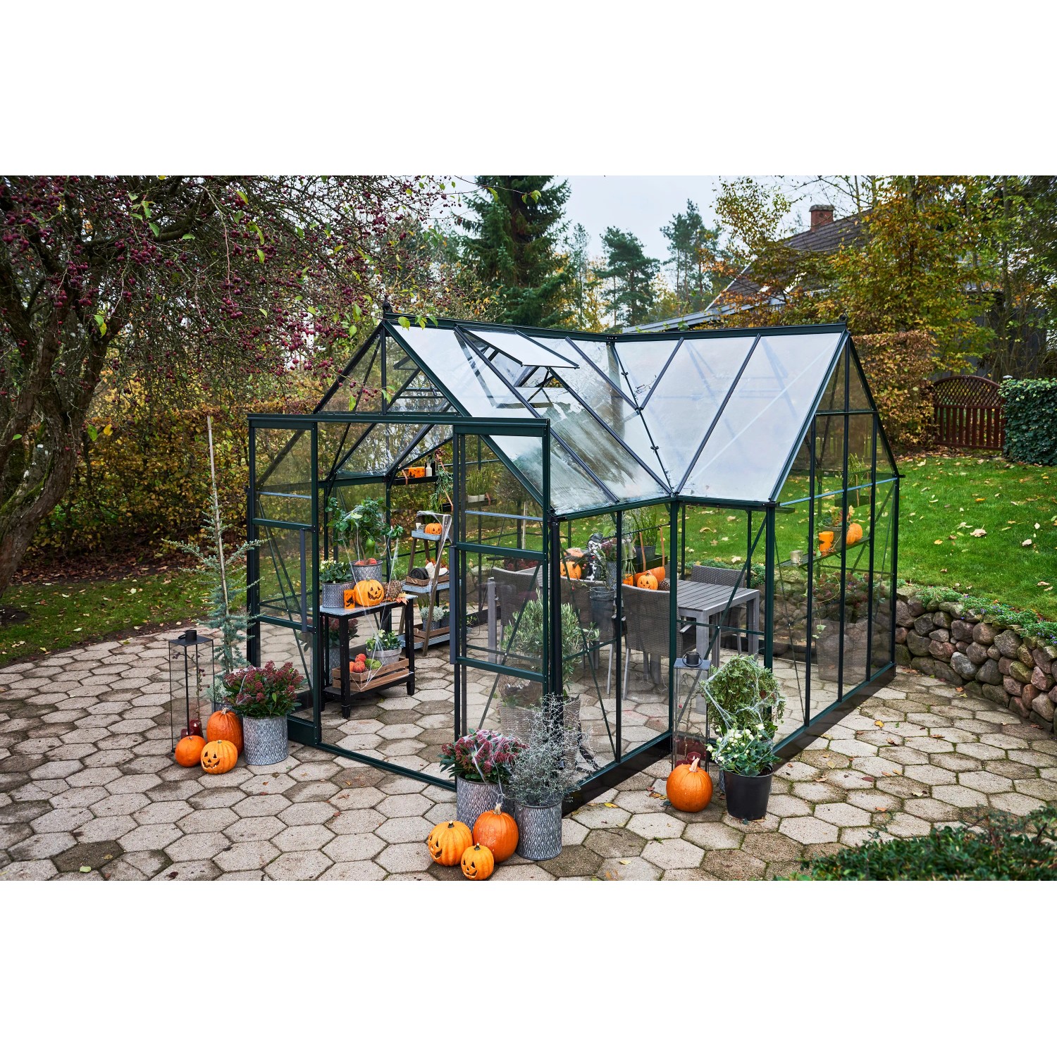 Halls Gewächshaus Garden Room, 12,9 m², grün, mit geöffneten Dachfenstern und herbstlicher Dekoration.