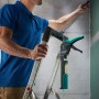 wolfcraft Kartuschenpresse MG 400 grün-schwarz hängt am Leiterhaken einer Aluleiter, Mann arbeitet an Wand.