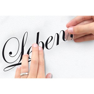 Anbringen des Komar Wandstickers "Träume" (70x50 cm) an einer weißen Wand.