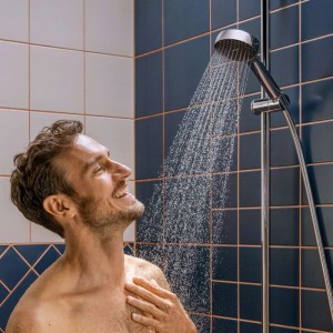 Mann unter Hansgrohe Activera Brauseset mit Duschstange (72cm) in Chrom beim Duschen.