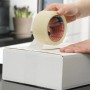 Tesapack Strong Packband beim Verschließen eines Kartons. Braunes Klebeband für sicheren Versand.