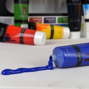 Artina Crylic Acrylfarbe, 24 Tuben. Blaue Farbe fließt aus einer Tube.