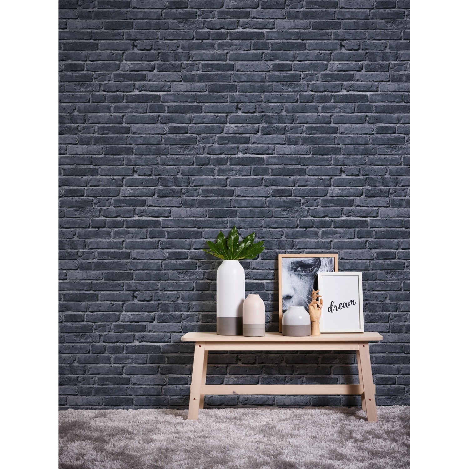 Vliestapete Steine in Schwarz und Grau an Wand, mit Deko auf einem Tisch.