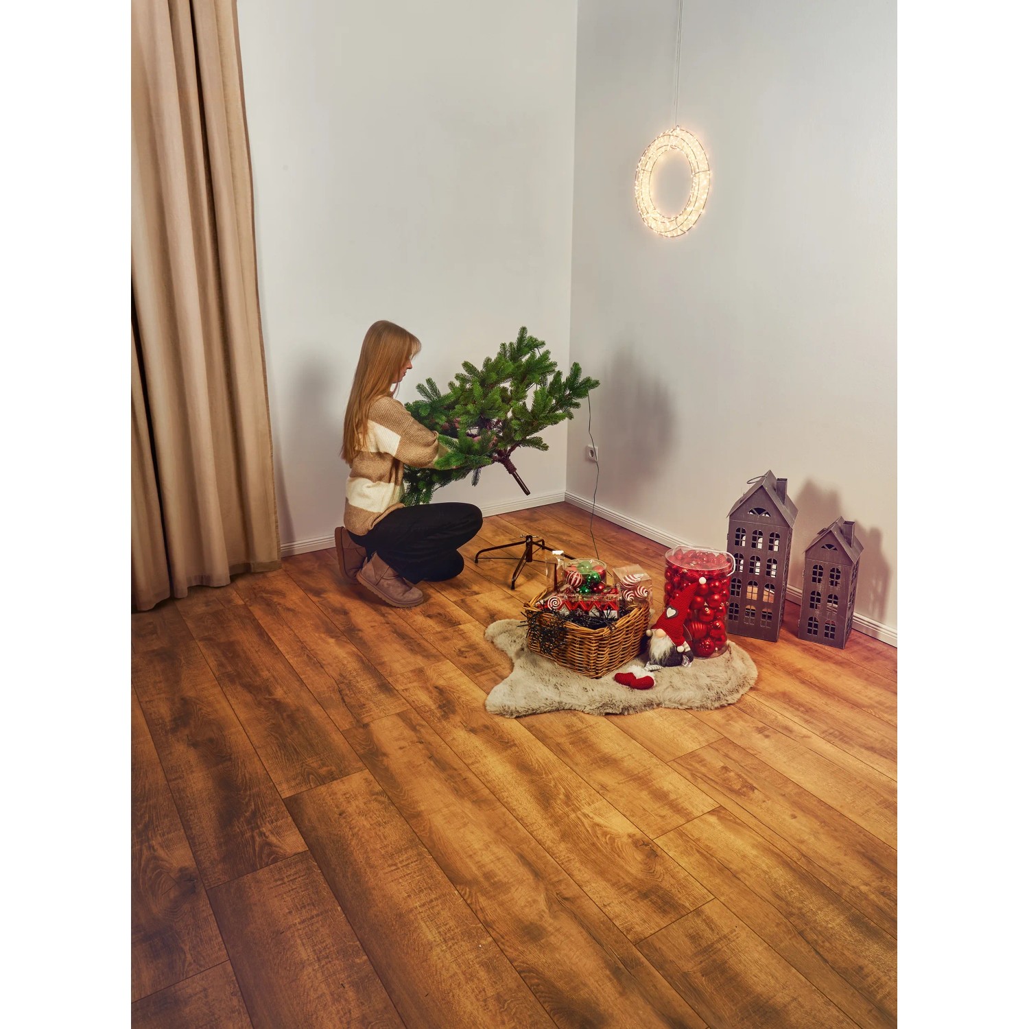 Frau setzt künstlichen LED Weihnachtsbaum Nagano 180 cm in Grün zusammen.