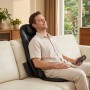 Mann entspannt auf hellem Sofa mit schwarzer HOMCOM Shiatsu Massagesitzauflage, hält Fernbedienung.