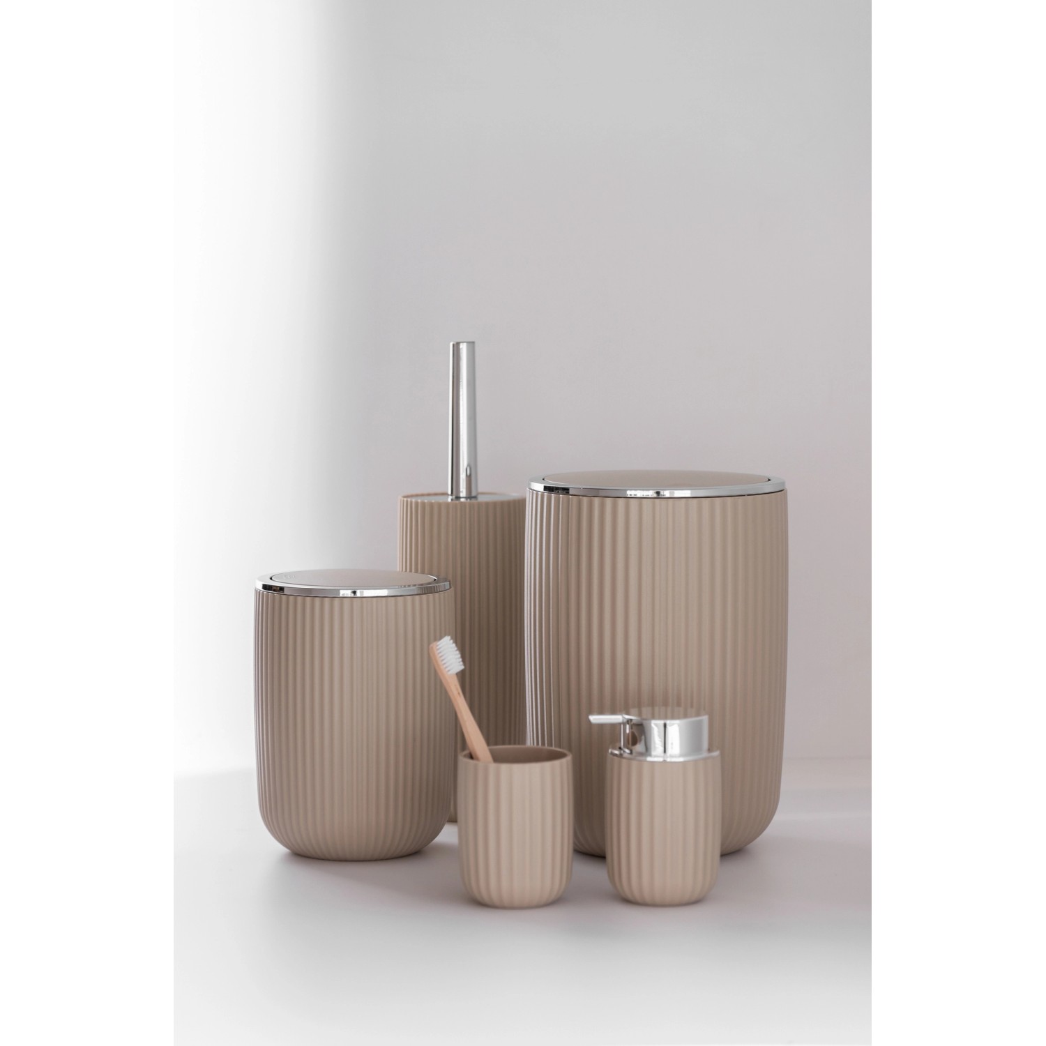 Beige Bad-Accessoires Agropoli: Kosmetikeimer, Seifenspender, WC-Garnitur und Zahnputzbecher.
