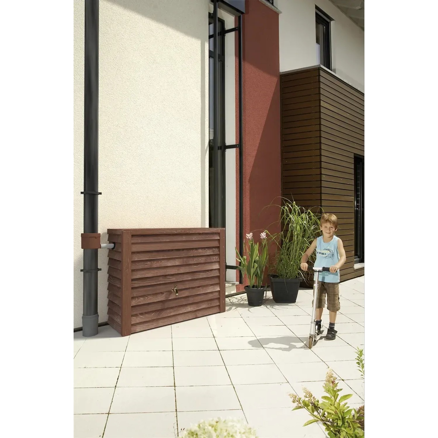 Garantia Regenwasser-Wandtank Woody 350 l Darkwood mit Kind auf Roller vor Hauswand.