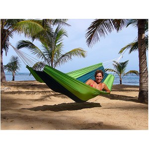 Frau entspannt in Amazonas Outdoor Hängematte (Camouflage) am Strand zwischen Palmen.