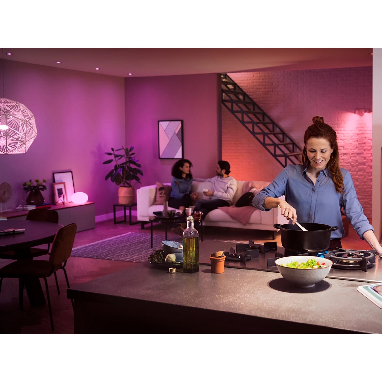 Szene mit Philips Hue Starter-Set: Frau kocht, Ambiente mit farbigen E27 Leuchtmitteln.