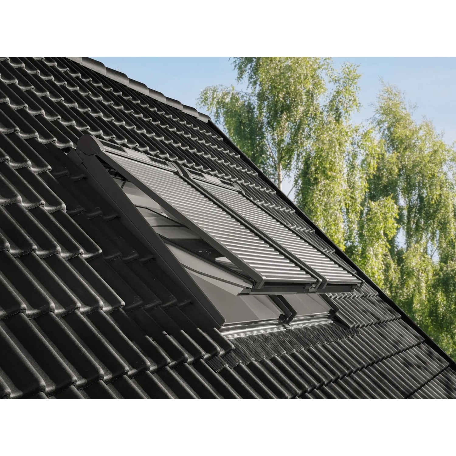 Solar Rollladen aus Aluminium für Velux Dachfenster, geschlossen auf dunklem Ziegeldach.