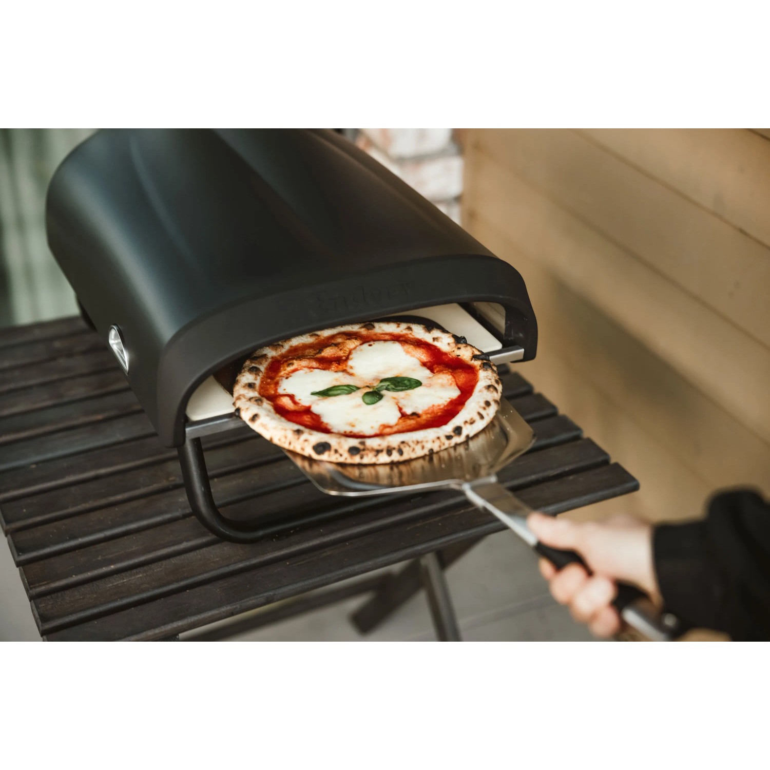 Enders Pizzaofen Paco mit Pizza auf Pizzaschieber vor dem Ofen.