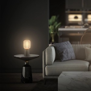 Brilo Tischleuchte Rist Rosegold auf Marmortisch neben Sofa. Design-Tischlampe mit Drahtkorb.