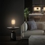 Brilo Tischleuchte Rist Rosegold auf Marmortisch neben Sofa. Design-Tischlampe mit Drahtkorb.