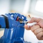Detailaufnahme: Hand wechselt Kohlebürste am blauen LUX Abbruchhammer 1300 W.