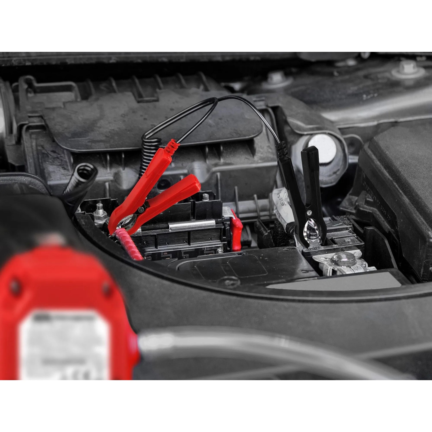 APA Ölabsaugpumpe 12V im Einsatz am Auto, mit Batterieklemmen an der Autobatterie.