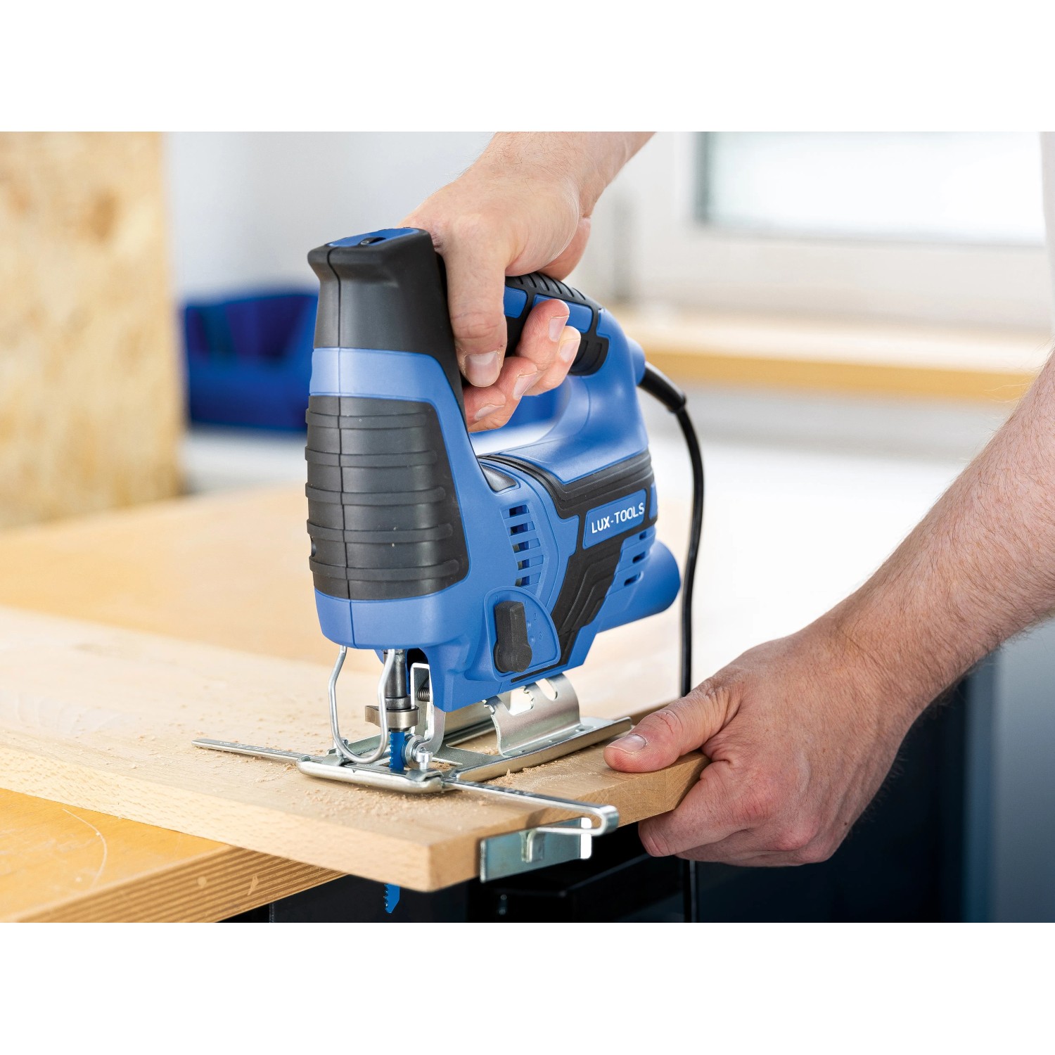 Blaue LUX Stichsäge E-STS-23 beim Sägen von Holz mit Parallelanschlag.