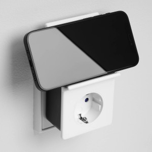 Weißes REV Ritter Induktions-Ladegerät mit Steckdose und Smartphone auf Ablage.