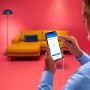 Mann steuert WiZ Außenleuchte per App auf Smartphone. Smarte Gartenbeleuchtung.