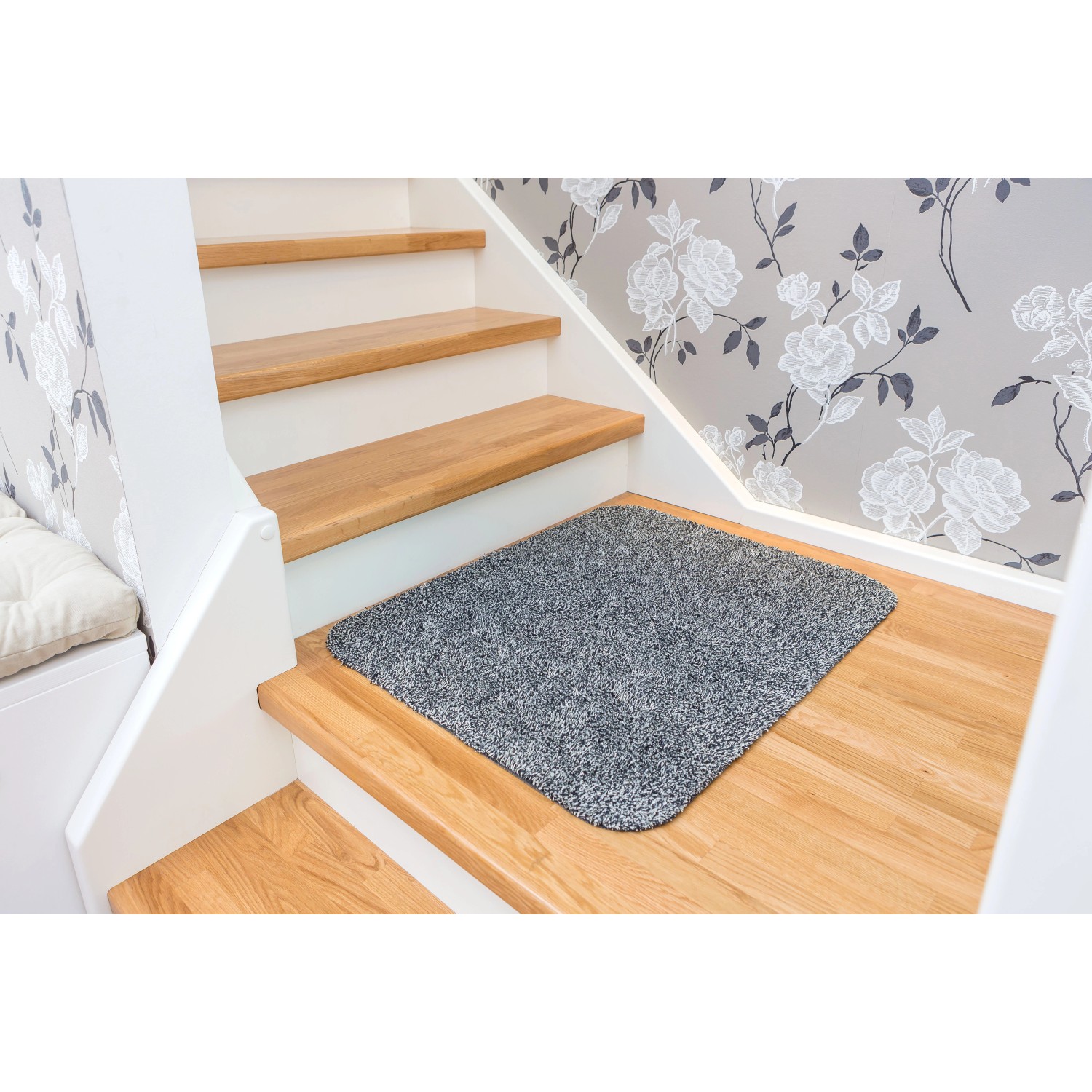 Anthrazitfarbene Astra Sauberlaufmatte Entra auf einer Holztreppe. Saugstarke Fußmatte, ca. 60x75 cm.