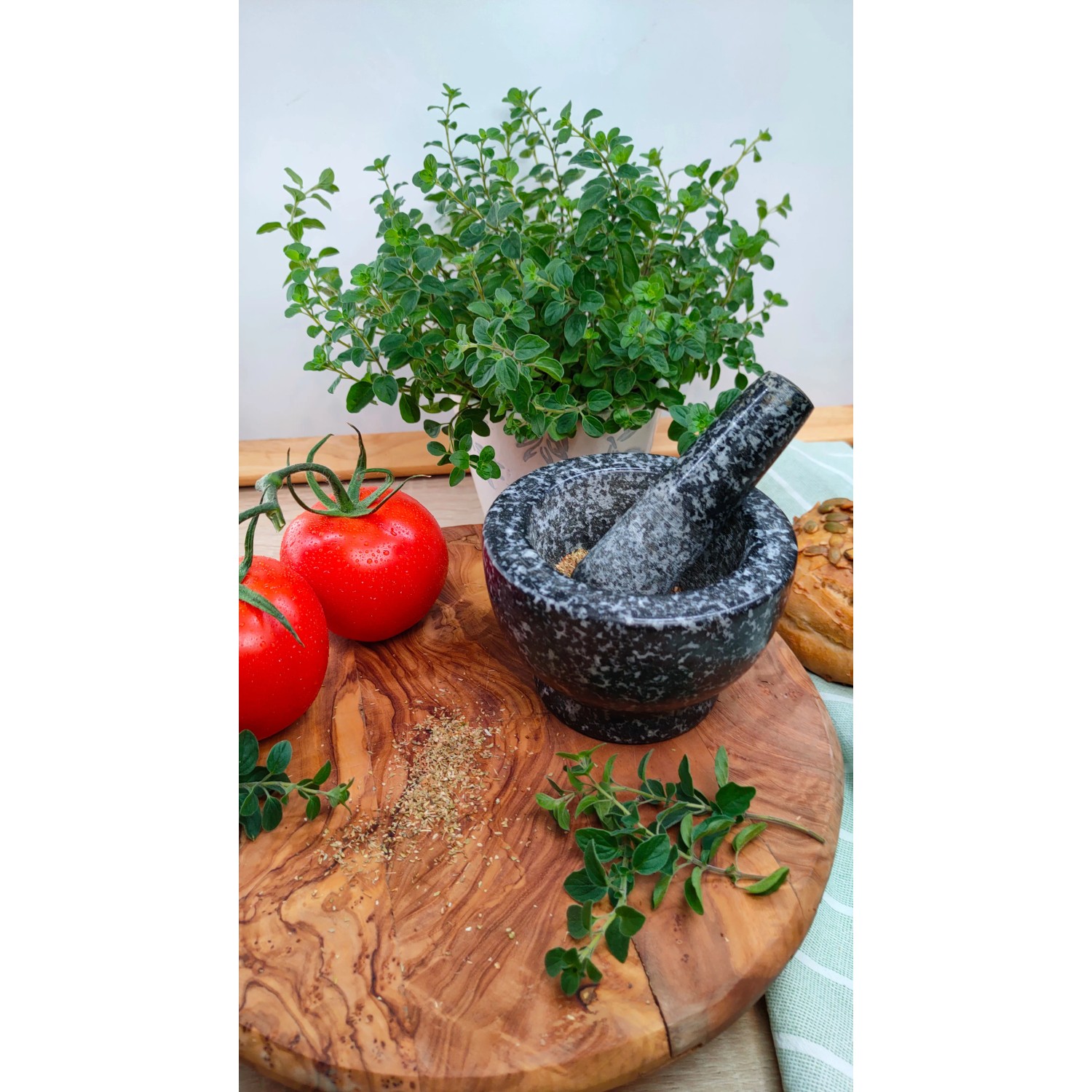 Blu Bio-Oregano im Topf mit Mörser, Tomaten und Gewürzen auf Holzbrett.
