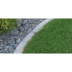 Graue Mähkante aus Beton zwischen Rasen und Steinen im Garten.