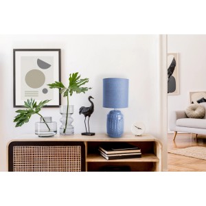 Blaue Näve Tischleuchte Erida aus Keramik mit Stoffschirm auf einem Sideboard.