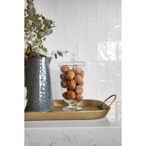 Szene mit glänzenden, weißen Artisa Wandfliesen, Krug, Nüssen im Glas und goldfarbenem Tablett.