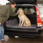 Heller Labrador sitzt auf LUX Abdeckvlies im Kofferraum eines Autos. Schutz vor Schmutz.